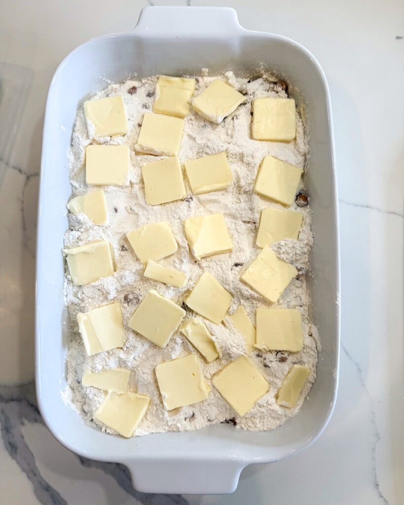 An unbaked cake mix topped with sliced butter.