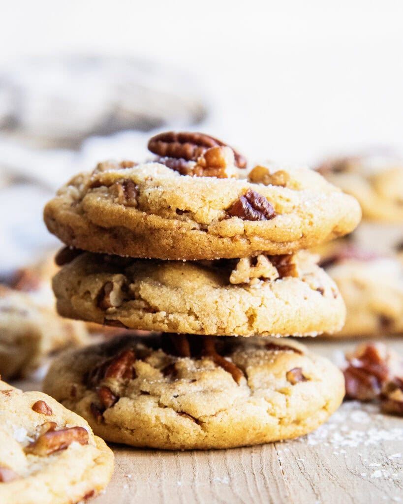A stack of three butter pecan cookies with a pecan half on top.