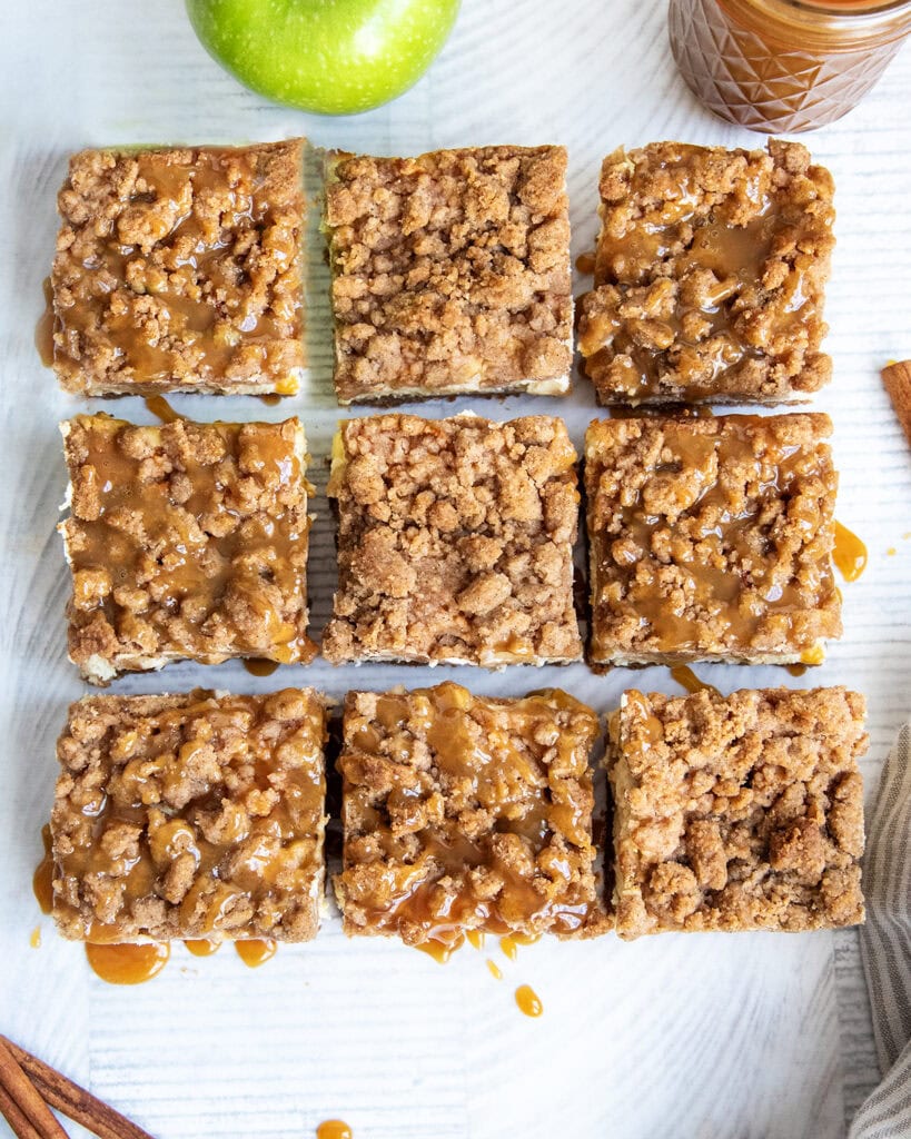 An above view of cheesecake bars with a crumb topping and caramel drizzled over the top.