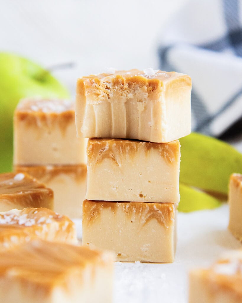 A stack of three pieces of caramel apple cider fudge, the top piece has a bite out of it.