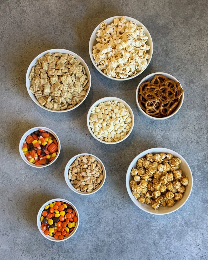 Small bowls of the ingredients needed to make a White Chocolate Halloween Snack Mix. 