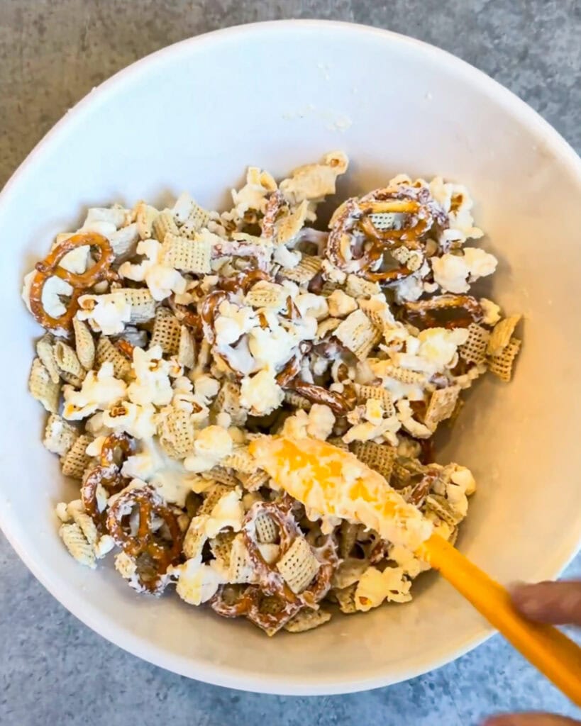 A bowl of white chocolate coated pretzels and popcorn.