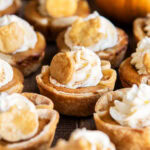 Mini pumpkin pies with whipped cream and a dash of cinnamon on top.
