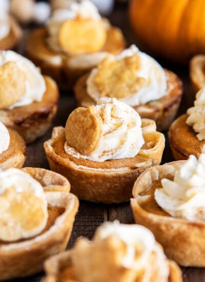 Mini pumpkin pies with whipped cream and a dash of cinnamon on top.