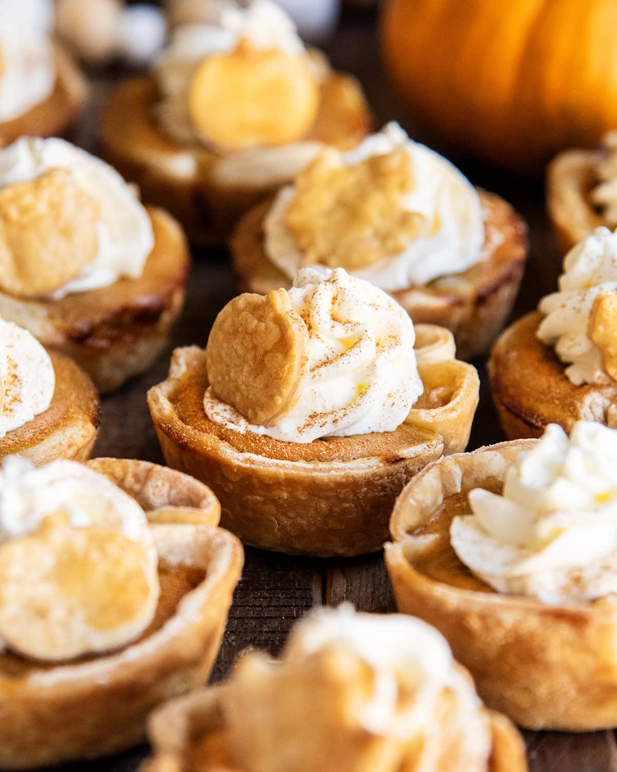 Mini pumpkin pies with whipped cream and a dash of cinnamon on top.