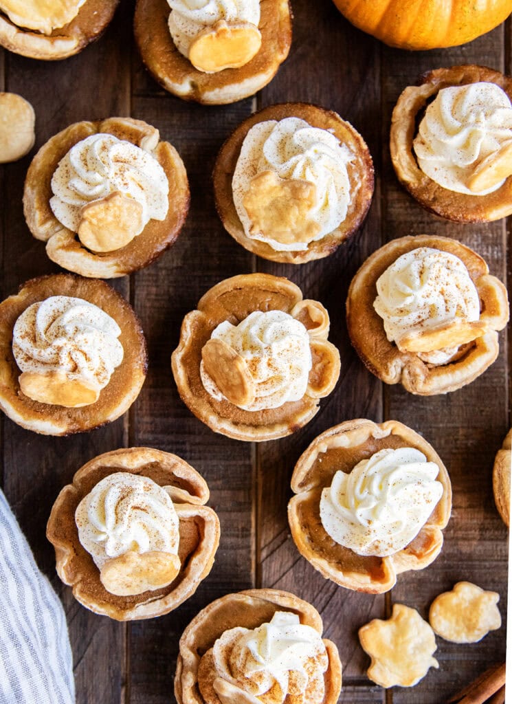 Mini pumpkin pies with whipped cream and a dash of cinnamon on top.