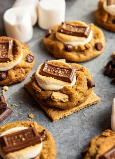 A pumpkin smore cookie on a graham cracker square. Its topped with a golden marshmallow and a Hershey square.