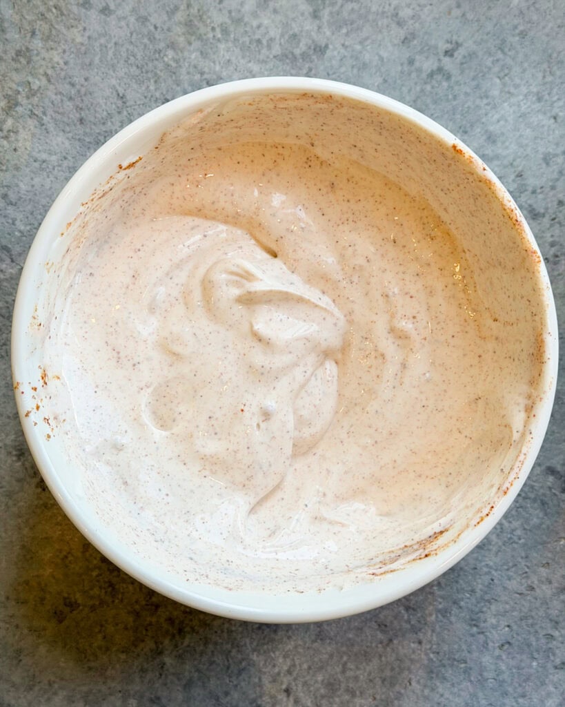 Sour cream mixed with taco seasoning in a bowl. 