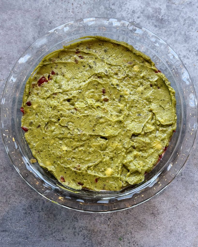 An above view of a layer of guacamole in a glass dish.