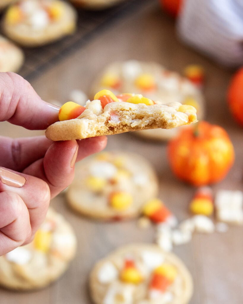 A hand holding a cookie loaded with candy corn pieces.