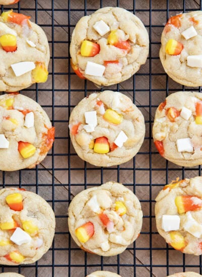Rows of white chocolate and candy corn cookies on a wire cooling rack.