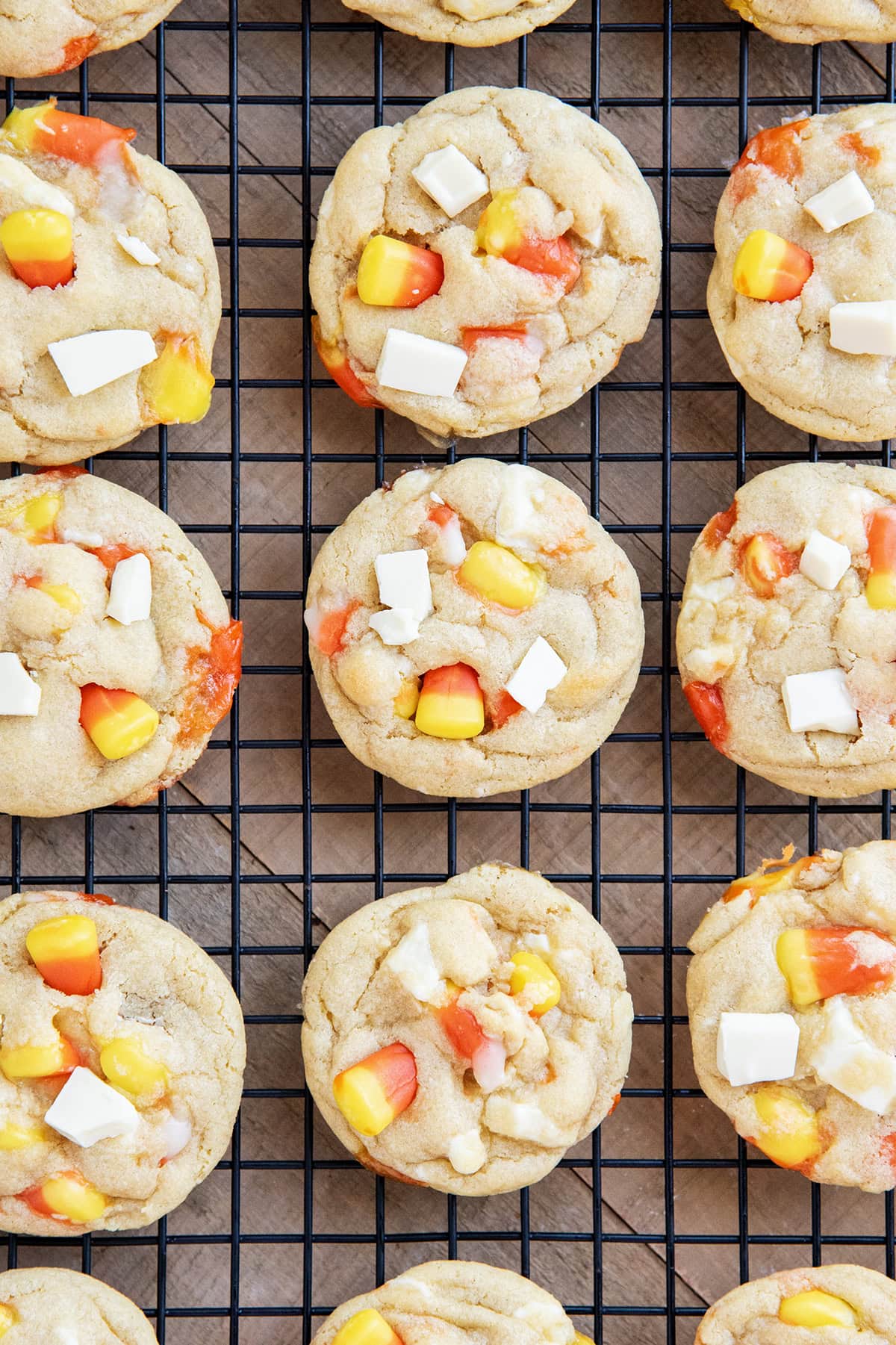 Rows of white chocolate and candy corn cookies on a wire cooling rack.