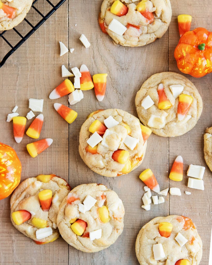An above view of candy corn and white chocolate topped cookies on a wooden table. 
