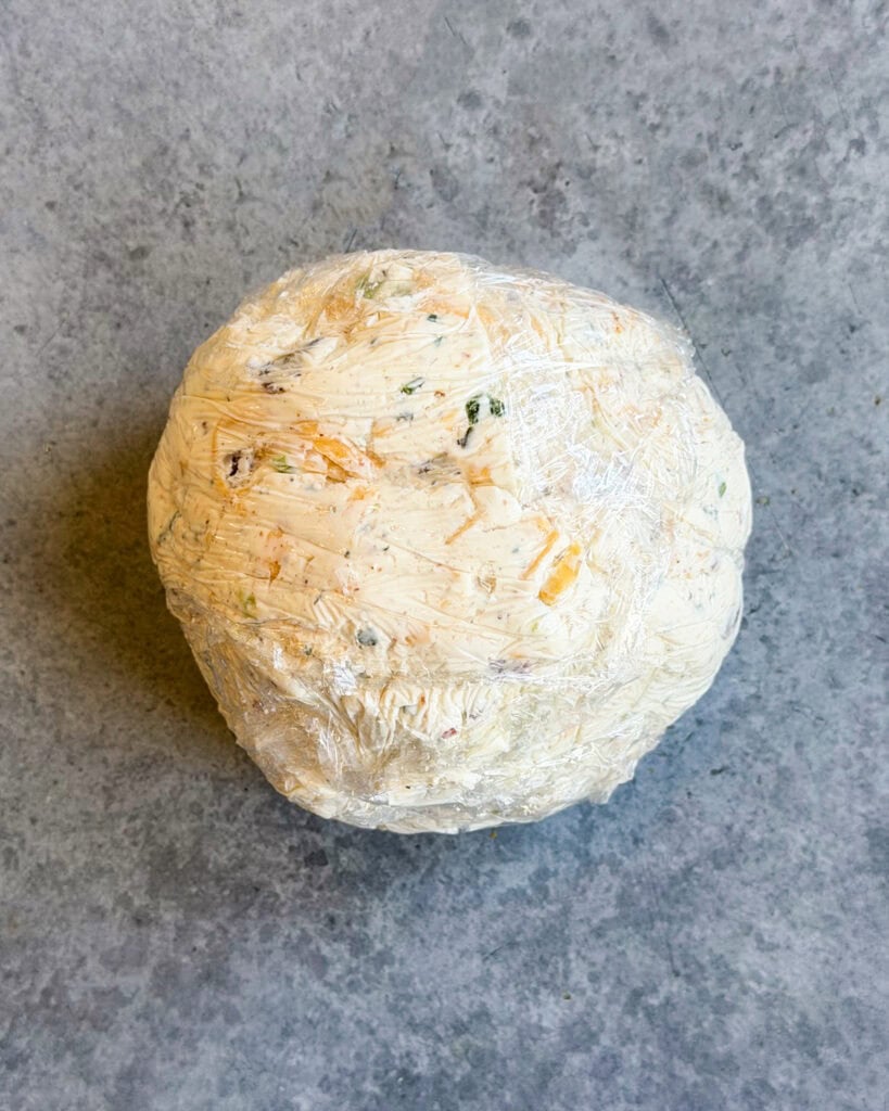 A cheese ball wrapped in plastic wrap.