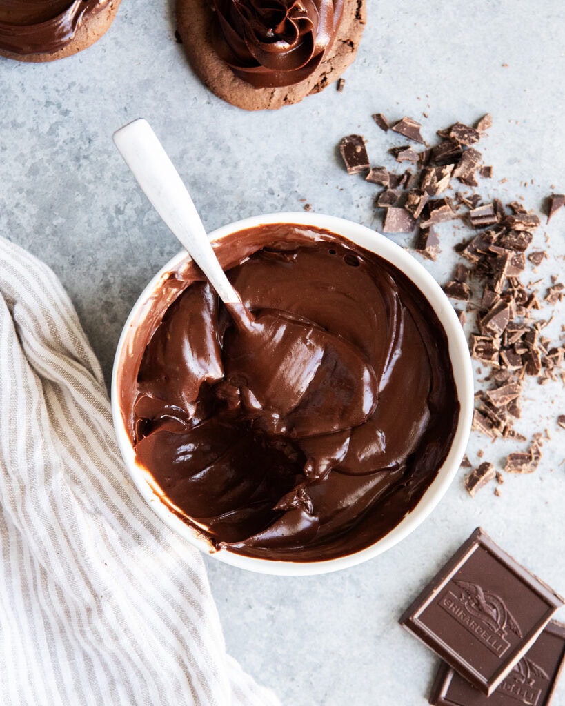 A bowl of thick chocolate ganache with a spoonful of it missing.