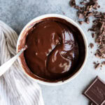 A bowl of chocolate ganache with a spoon in it.