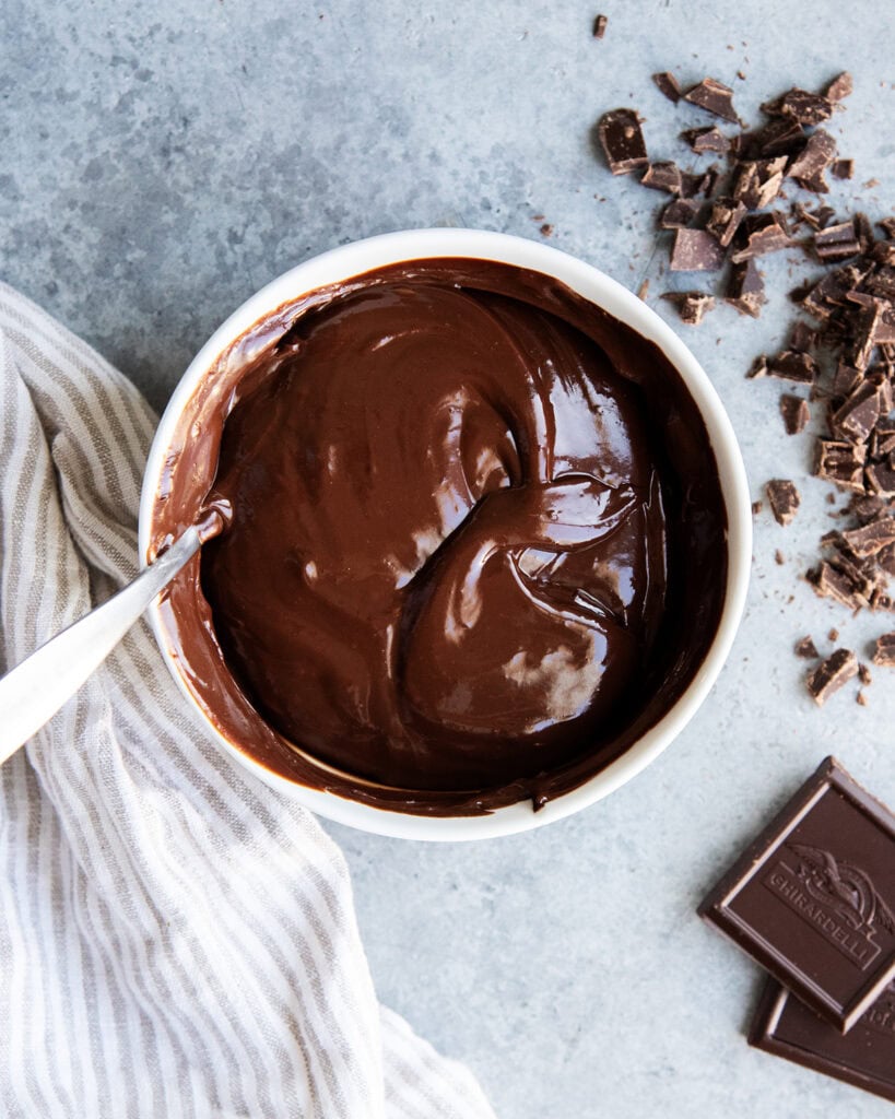 A bowl of chocolate ganache with a spoon in it.