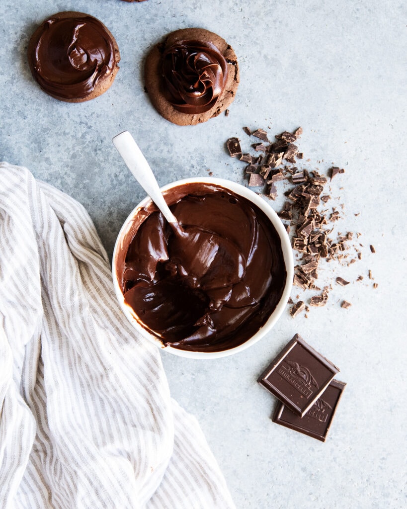 A bowl of thick chocolate ganache with a spoonful of it missing.