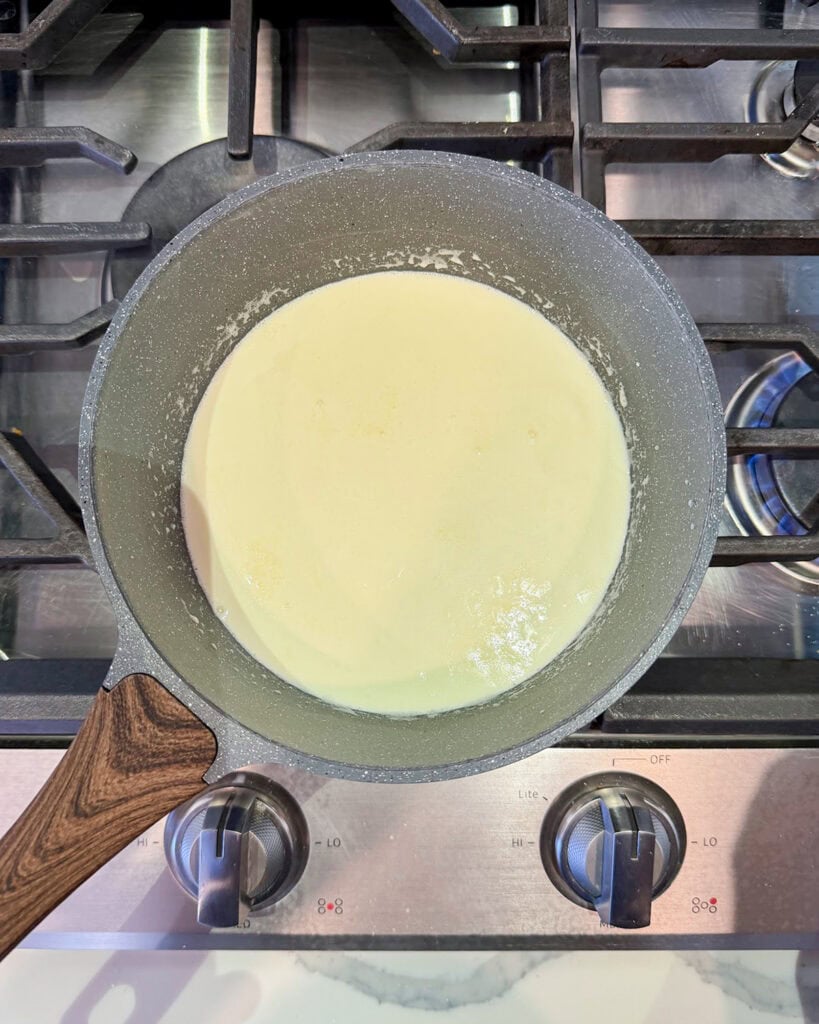Heavy cream heating in a small pot.