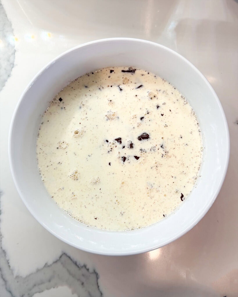 A bowl of hot cream over chopped chocolate.