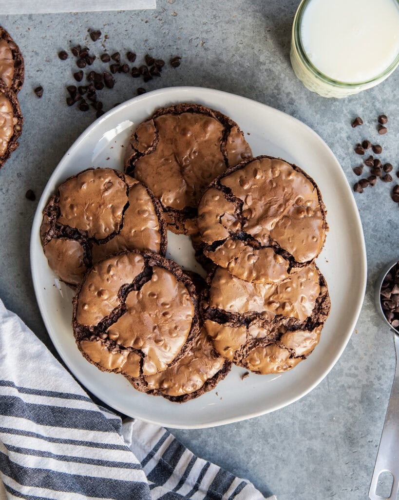 A plate of chocolate brownie cookies on a plate with crinkly tops.
