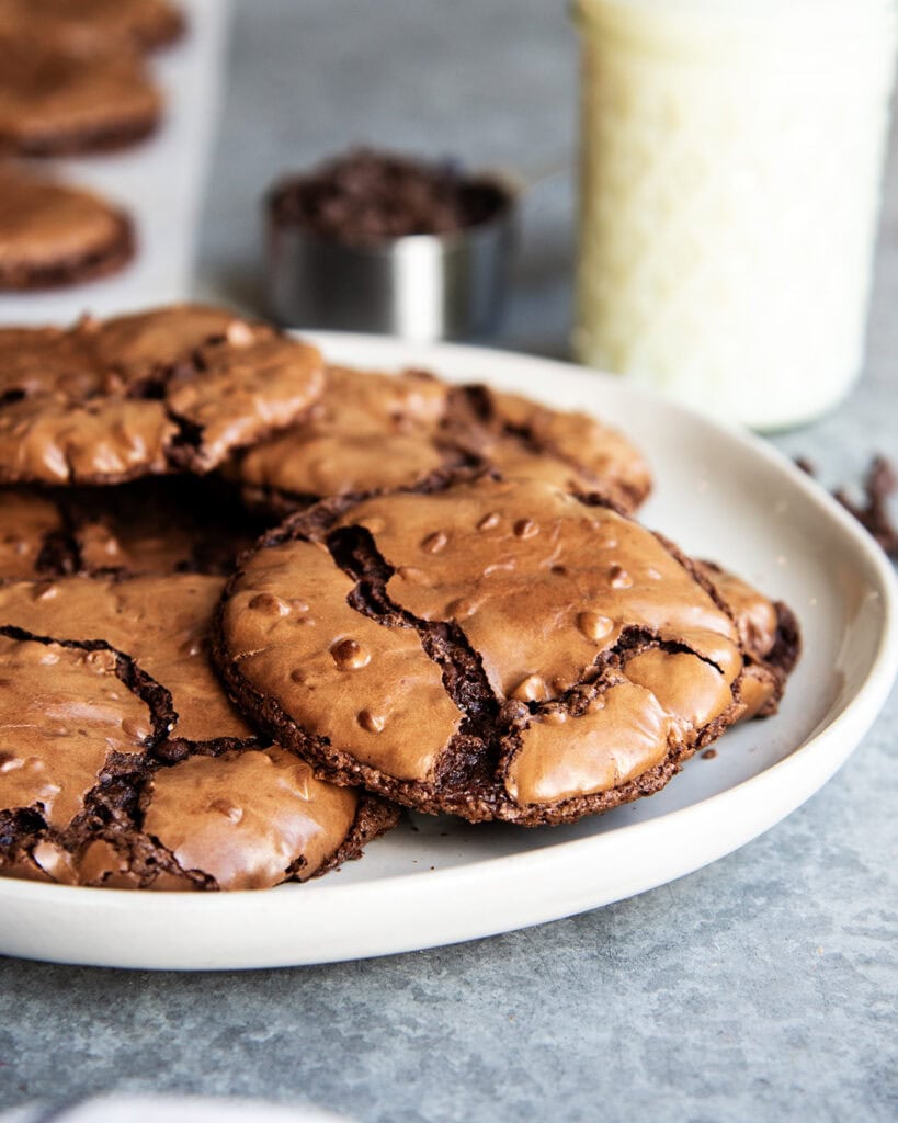 A plate of chocolate brownie cookies on a plate with crinkly tops.
