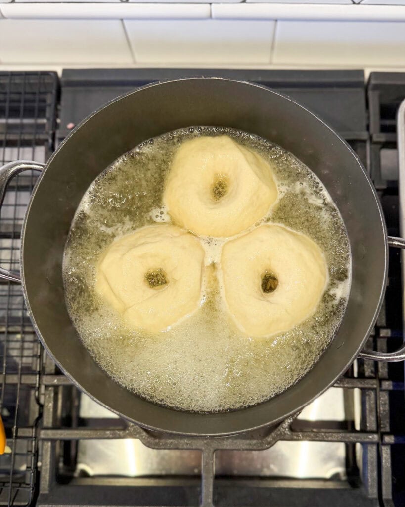 Three bagels boiling in water.
