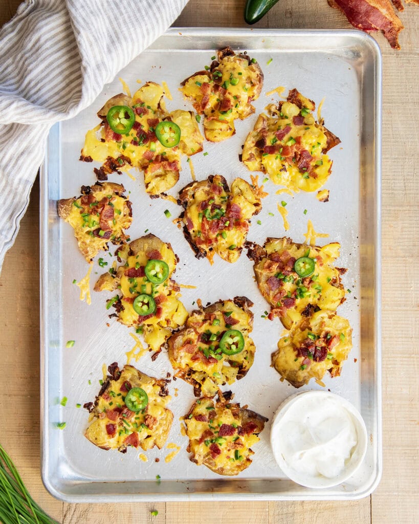 An above view of crispy jalapeno popper smashed potatoes on a metal cookie sheet.