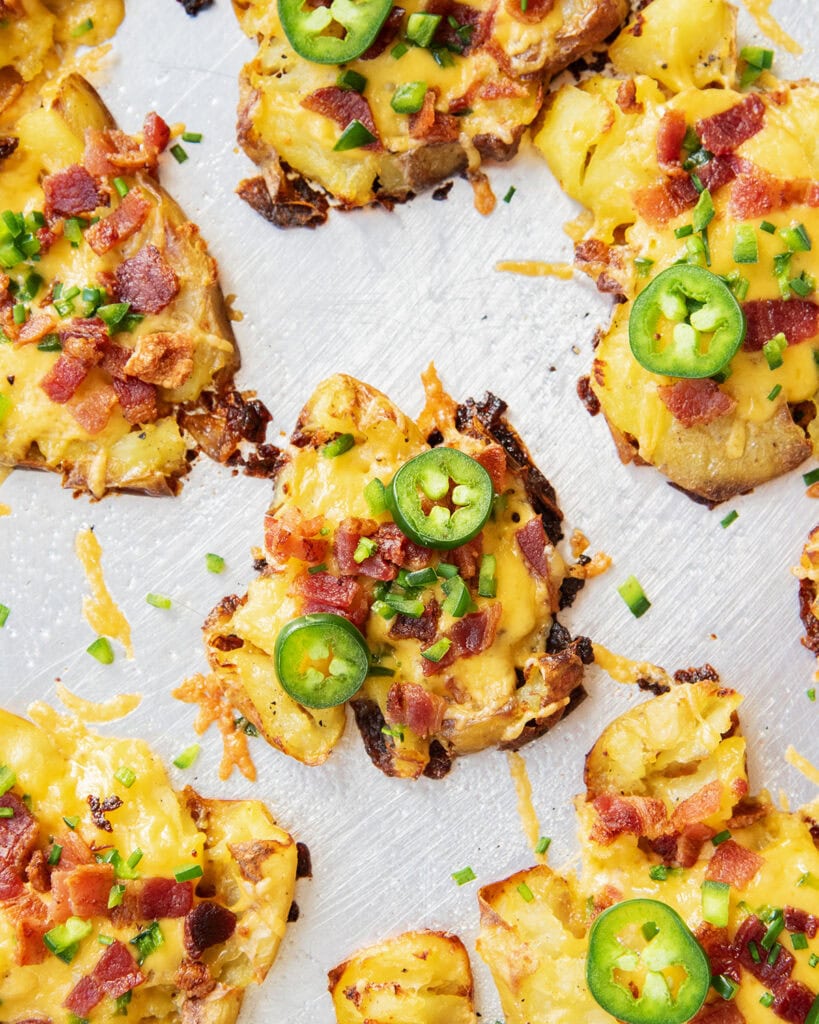 An above view of crispy jalapeno popper smashed potatoes on a metal cookie sheet.