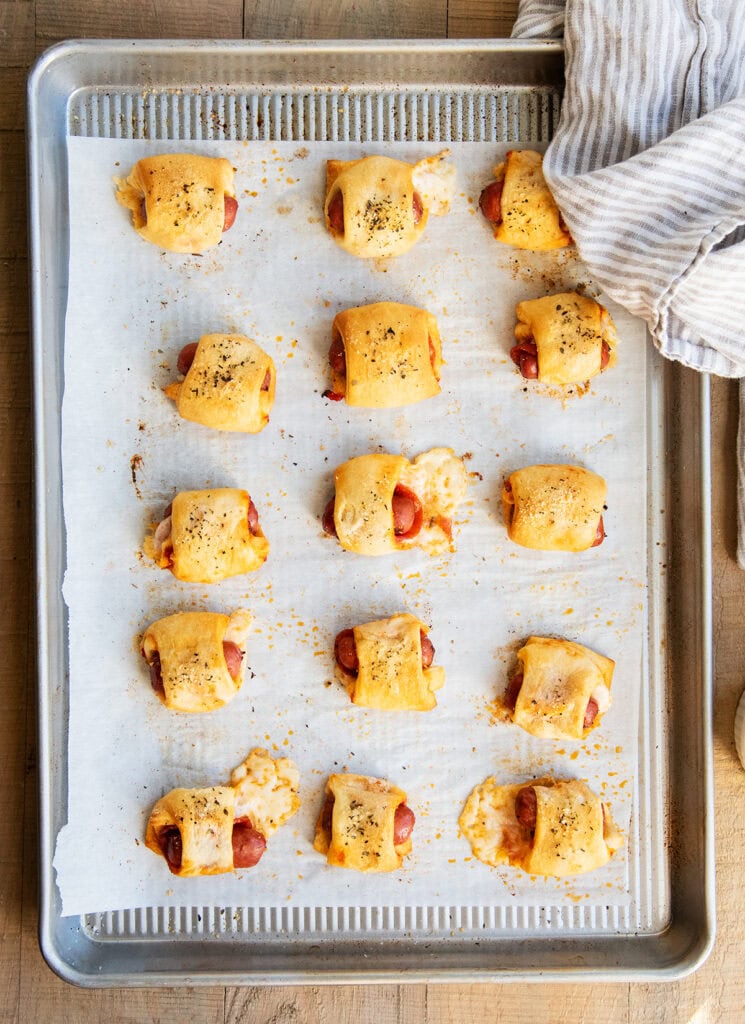 Rows of pizza pigs in a blanket on a cookie sheet.