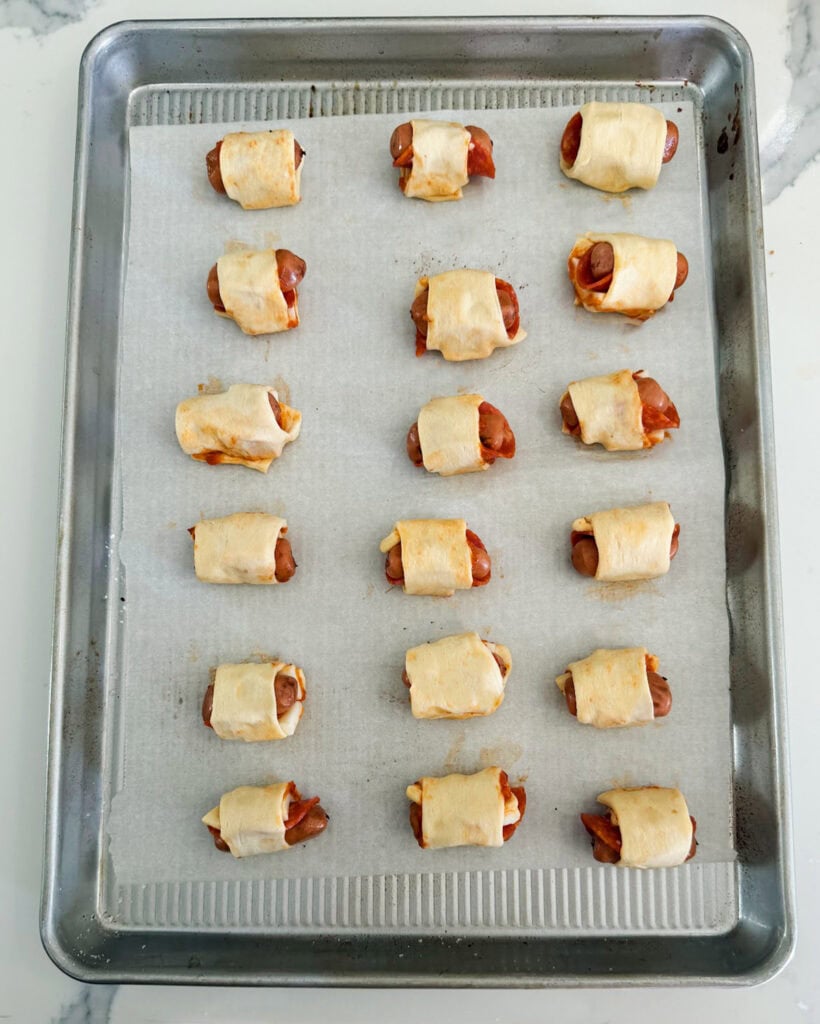 Unbaked pigs in a blanket on a cookie sheet.