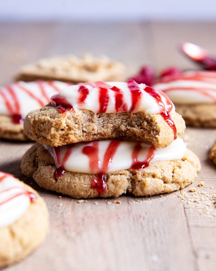 A stack of two Raspberry Cheesecake Cookies, and the top cookie has a bite out of it.