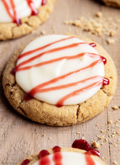 A Raspberry cheesecake cookie with cream cheese frosting, and a drizzle of raspberry sauce on top.
