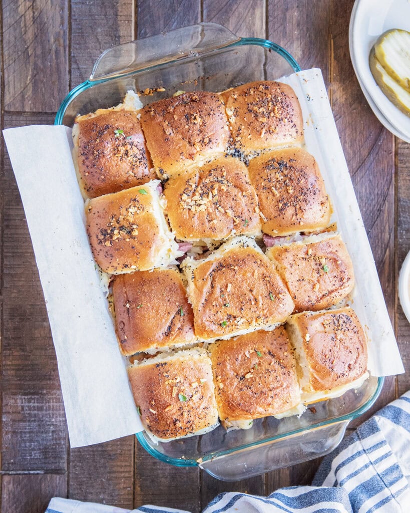 A glass dish full of Reuben Slider sandwiches.