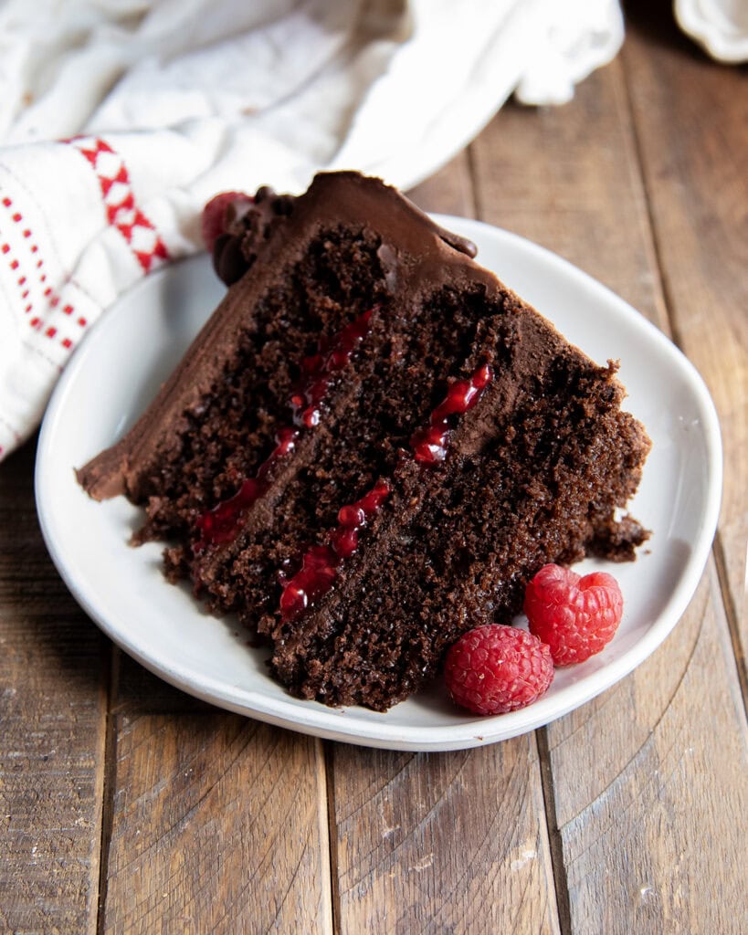 A slice of triple layer chocolate raspberry cake laying side ways on a plate.