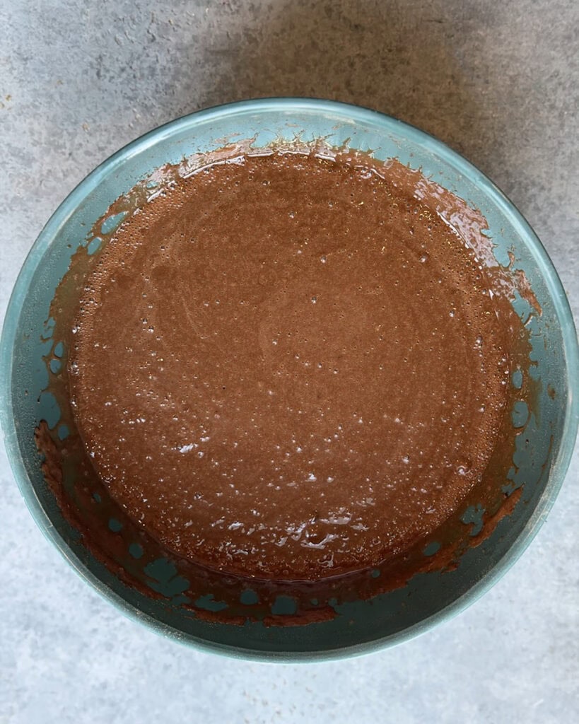 A runny chocolate cake batter in a turquoise bowl. 