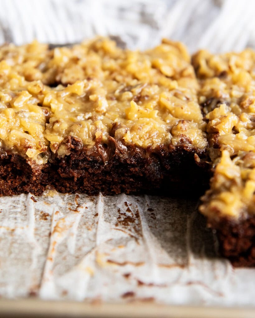 A German Chocolate Texas Sheet Cake in a pan lined with parchment paper. 