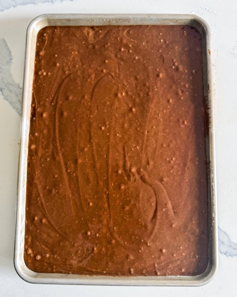 A jelly roll pan with chocolate cake batter in it.
