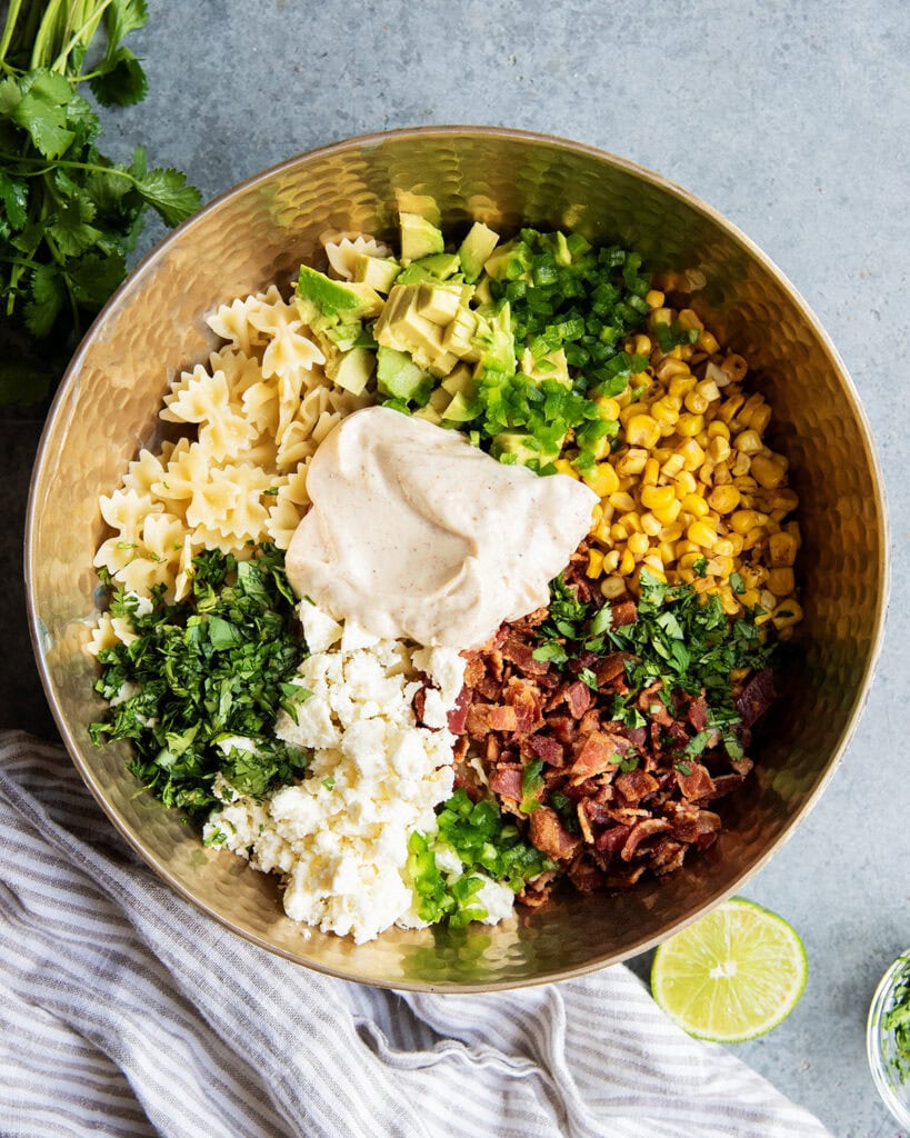 An above view of a bowl of pasta salad with a creamy chipotle dressing, corn, bacon, cilantro, and jalapenos.