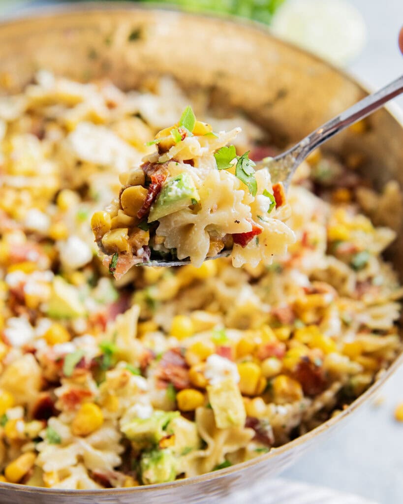 A spoonful of Mexican street corn pasta salad loaded with corn, bacon, cotija, and avocado.
