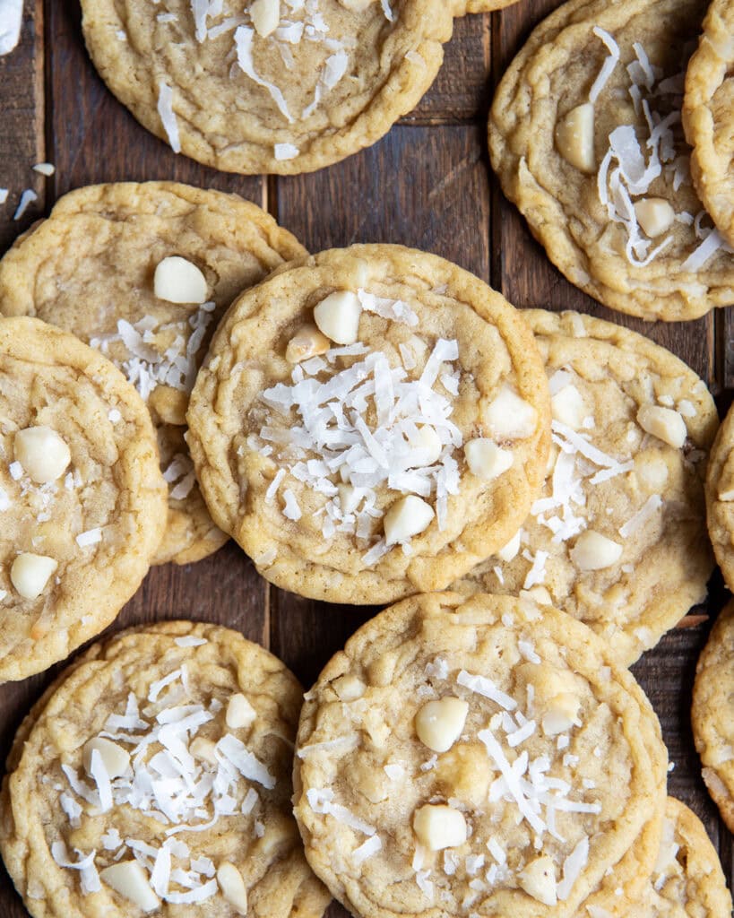 A pile of coconut and macadamia nut cookies on a wooden table.