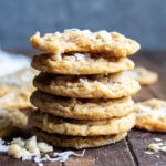 A stack of six coconut macadamia nut cookies, the top cookie has a bite out of it.