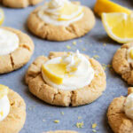 Lemon cream pie cookies with whipped cream and a lemon wedge on top on the counter.