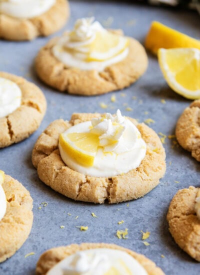 Lemon cream pie cookies with whipped cream and a lemon wedge on top on the counter.