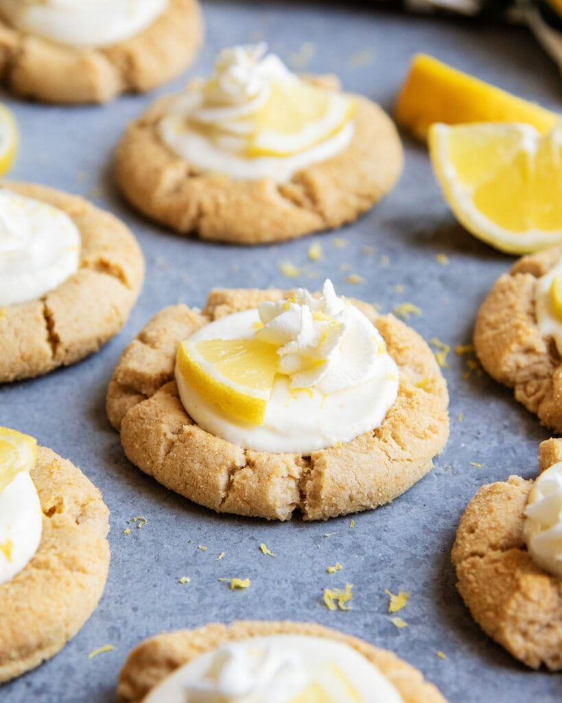 Lemon cream pie cookies with whipped cream and a lemon wedge on top on the counter.