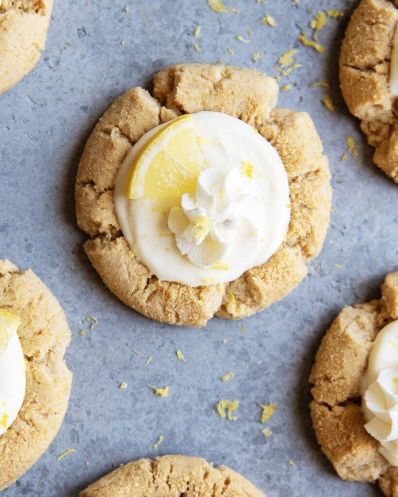 An above view of lemon cream pie cookies topped with a dollop of whipped cream and a lemon wedge.
