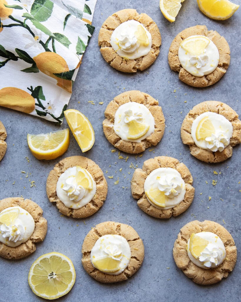 An above view of lemon cream pie cookies topped with a dollop of whipped cream and a lemon wedge.