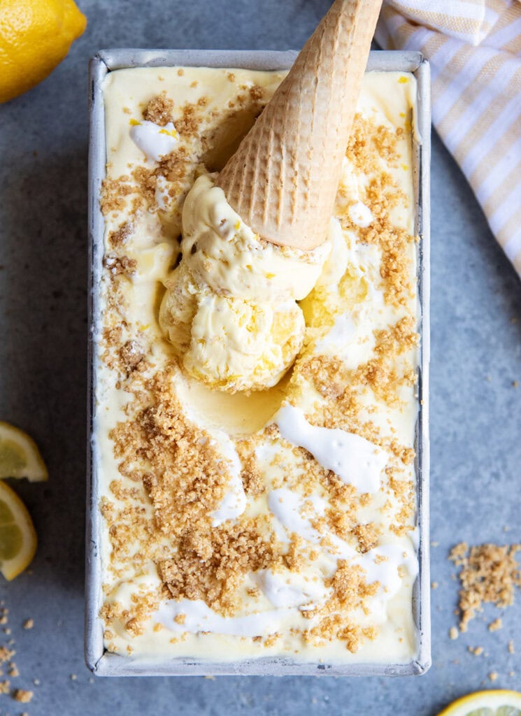 An above view of an ice cream cone of lemon cream pie ice cream in a container of ice cream.