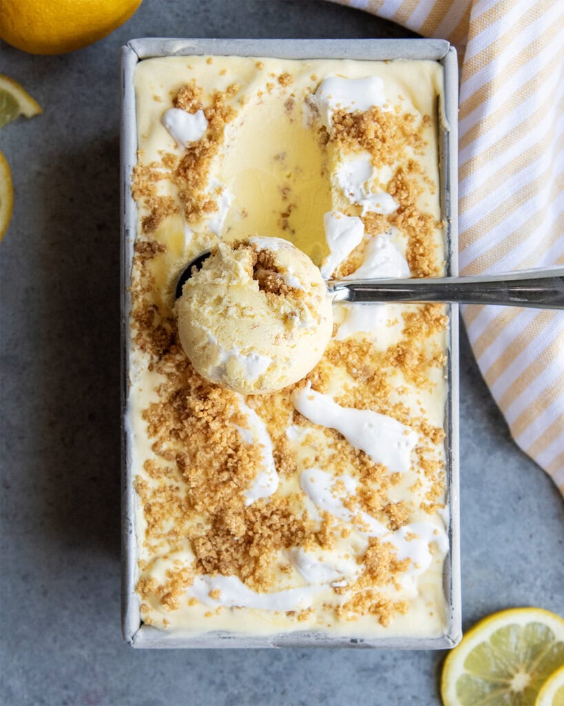 An above view of a scoop of lemon cream pie ice cream in a container of ice cream.