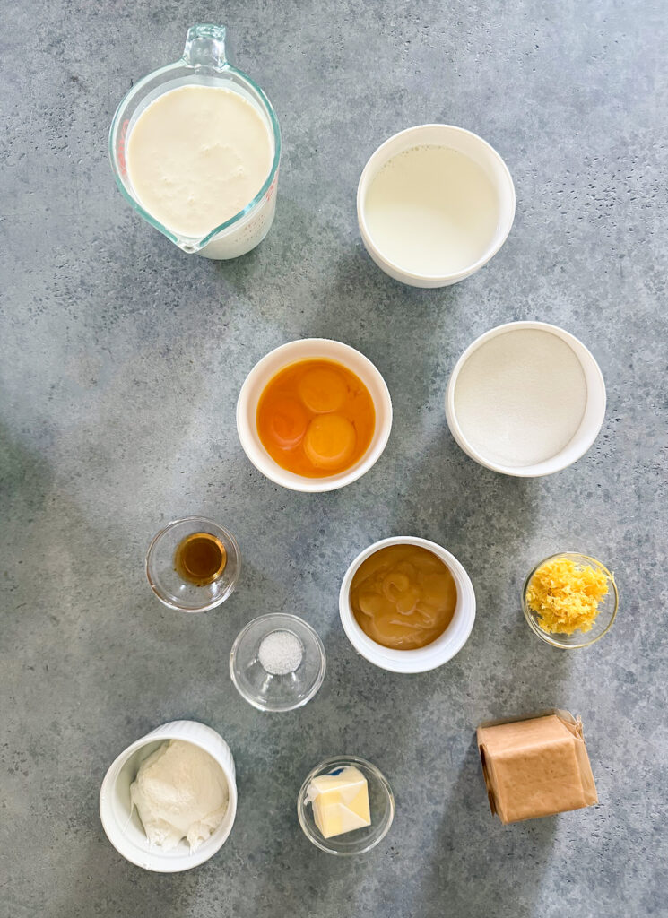 The ingredients needed to make lemon cream pie ice cream, including lemon zest, graham cracker crumbs, eggs, cream, milk, and sugar.